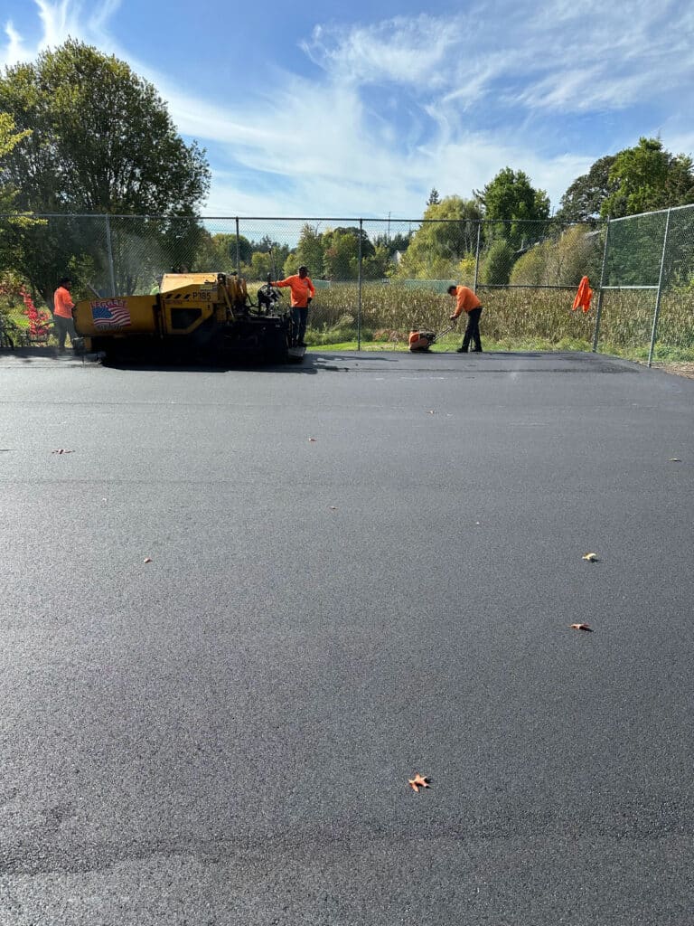 Crew working on asphalt tennis court paving